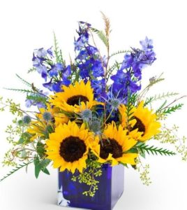 Send this wildly perfect flower bouquet of sunflowers, blue delphiniums, and greenery of seeded eucalyptus in a blue cube vase to someone you want to give the gift of land and sky to.